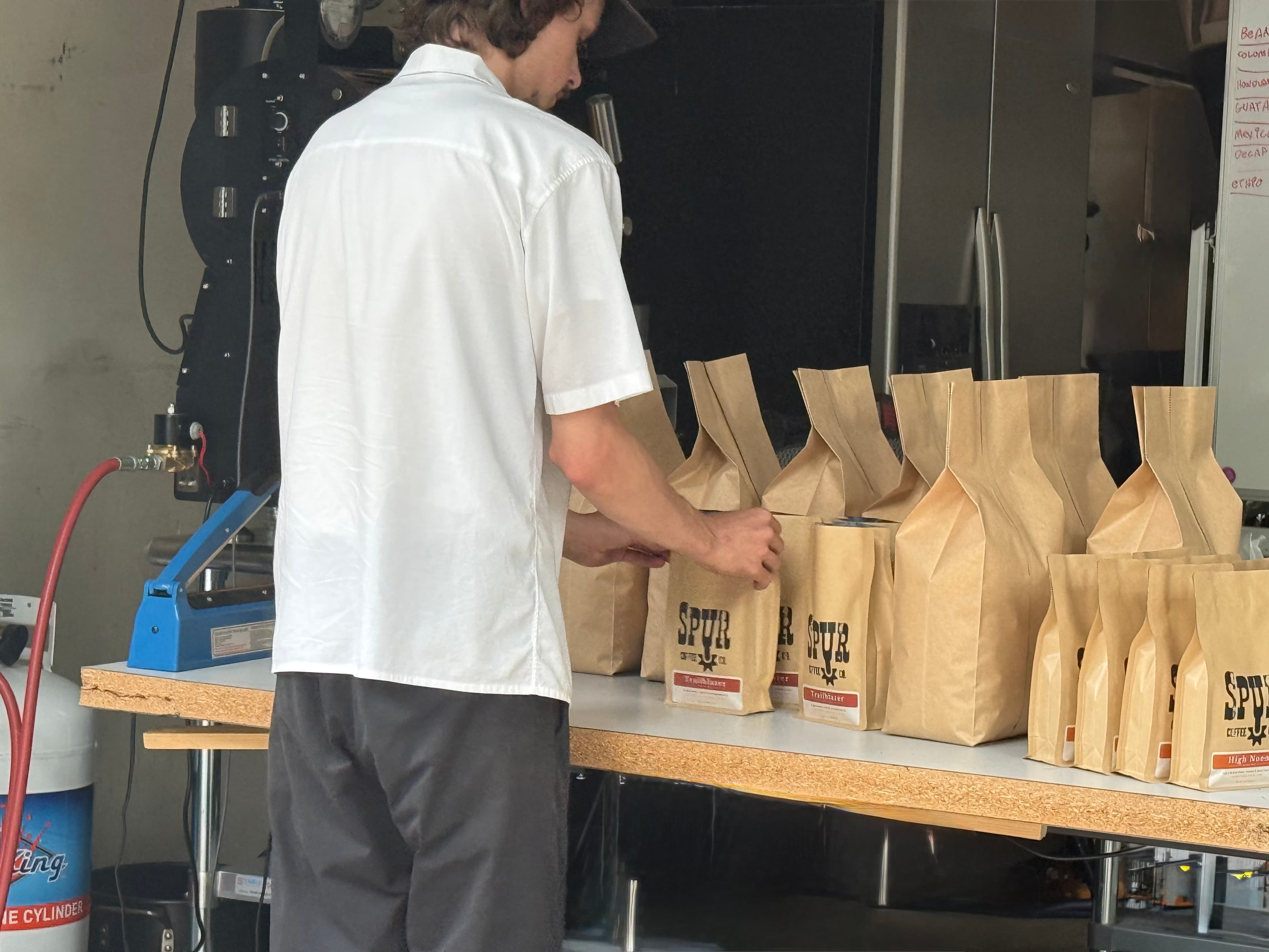 Packing fresh-roasted Spur Coffee bags by hand
